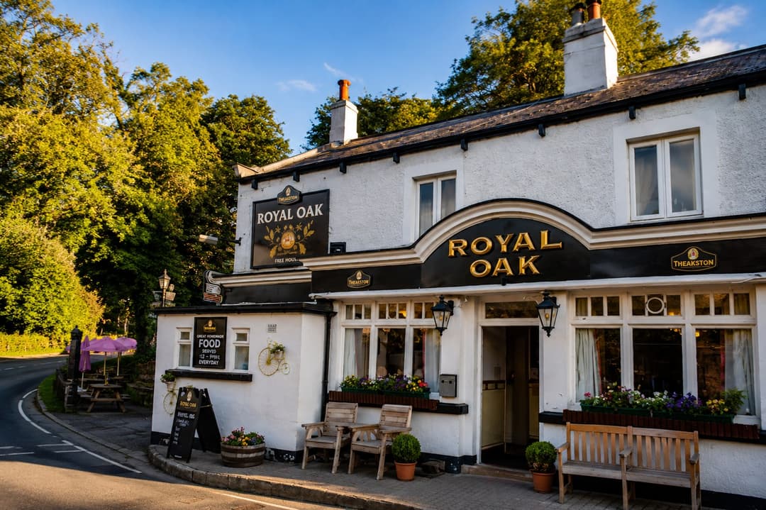 The white-painted exterior of the Royal Oak pub in Pateley Bridge, with hanging Theakston signs, flower boxes and outdoor benches
