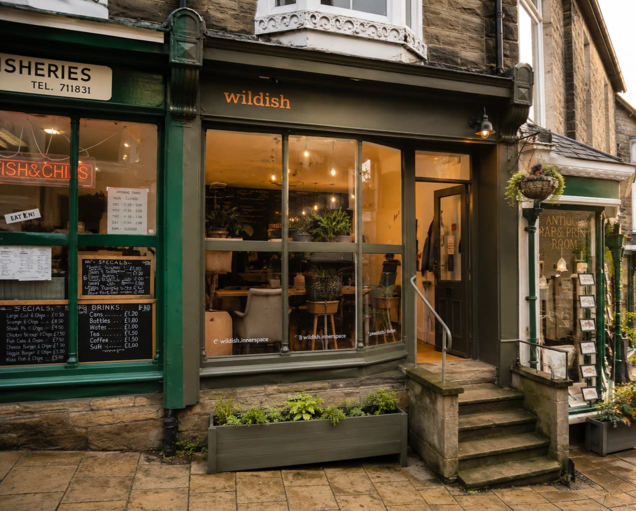 The green-painted Wildish shopfront on Pateley Bridge High Street, with warm lighting showing cafe seating inside and stone steps up to the door