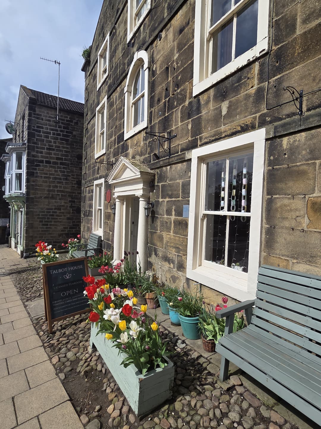The entrance to Talbot House with a planter of red, yellow and white tulips and an OPEN sign by the door