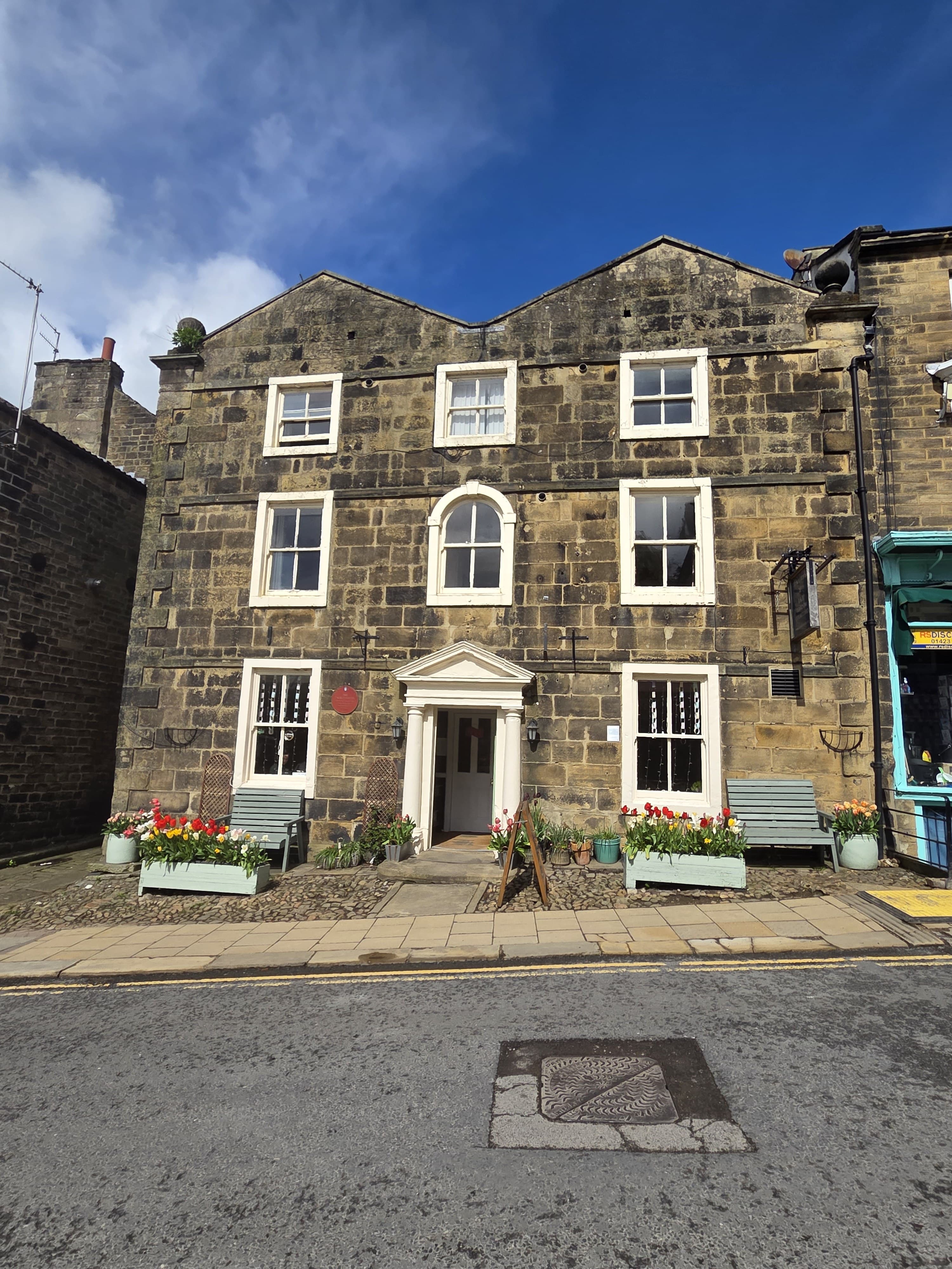 Talbot House seen from across the High Street, its Georgian stone facade under a clear blue sky