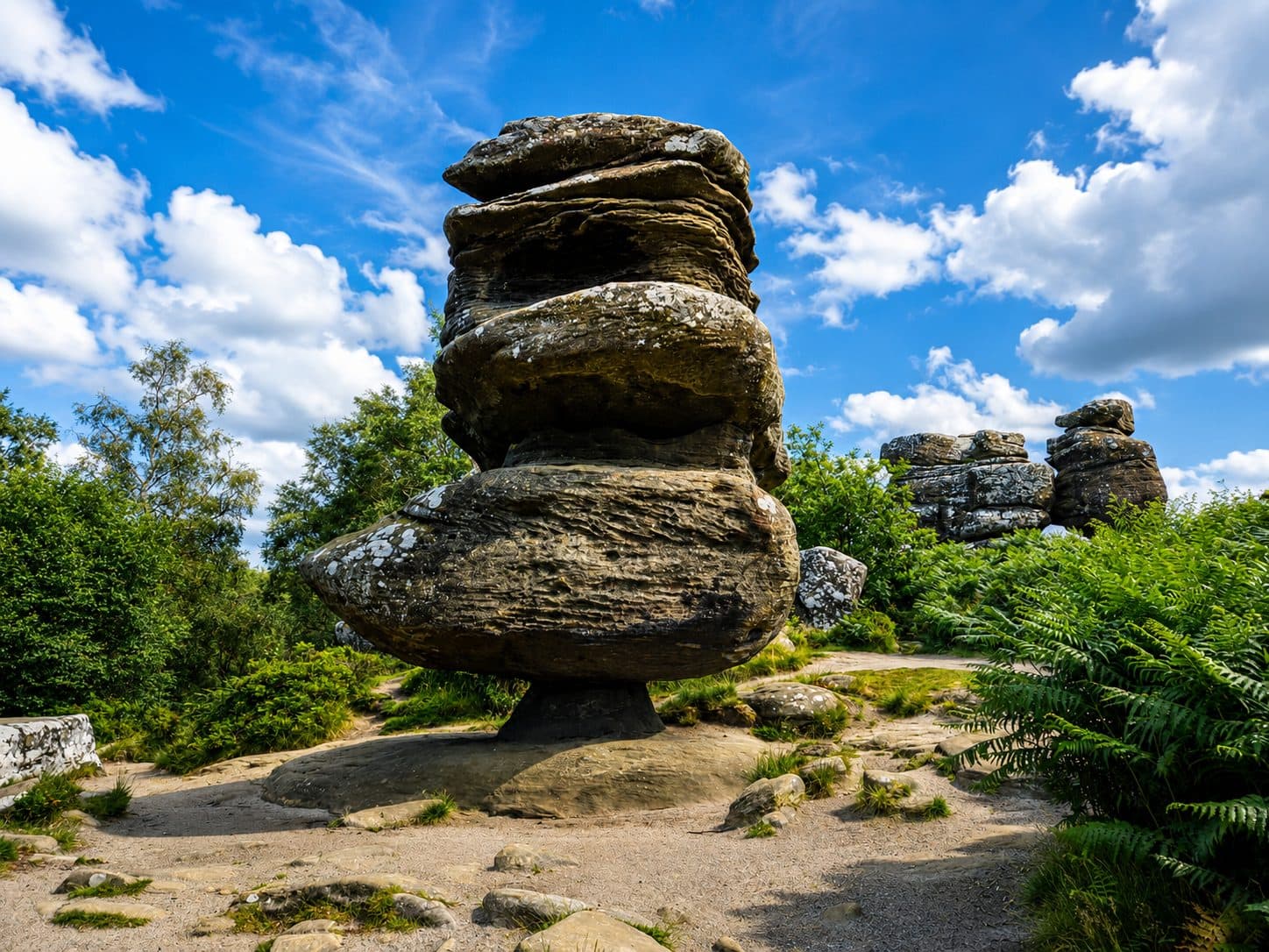 A tall balanced rock formation at Brimham Rocks stacked on a narrow base, with further formations visible behind