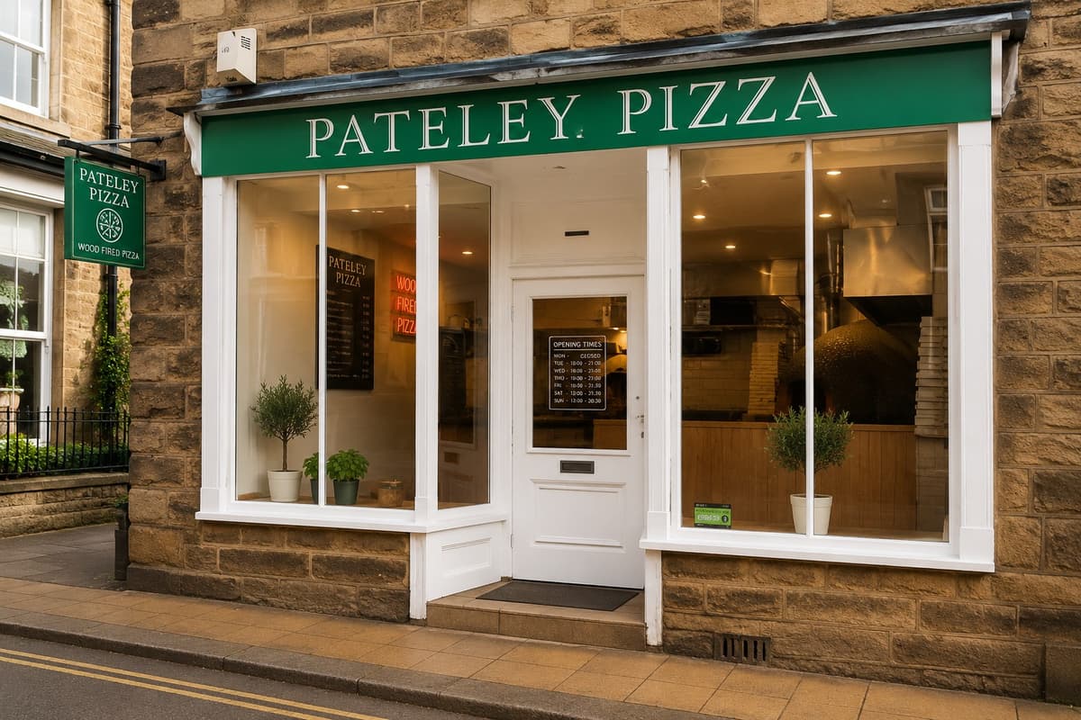 The green and white Pateley Pizza shopfront on the High Street, with the open kitchen visible through the window