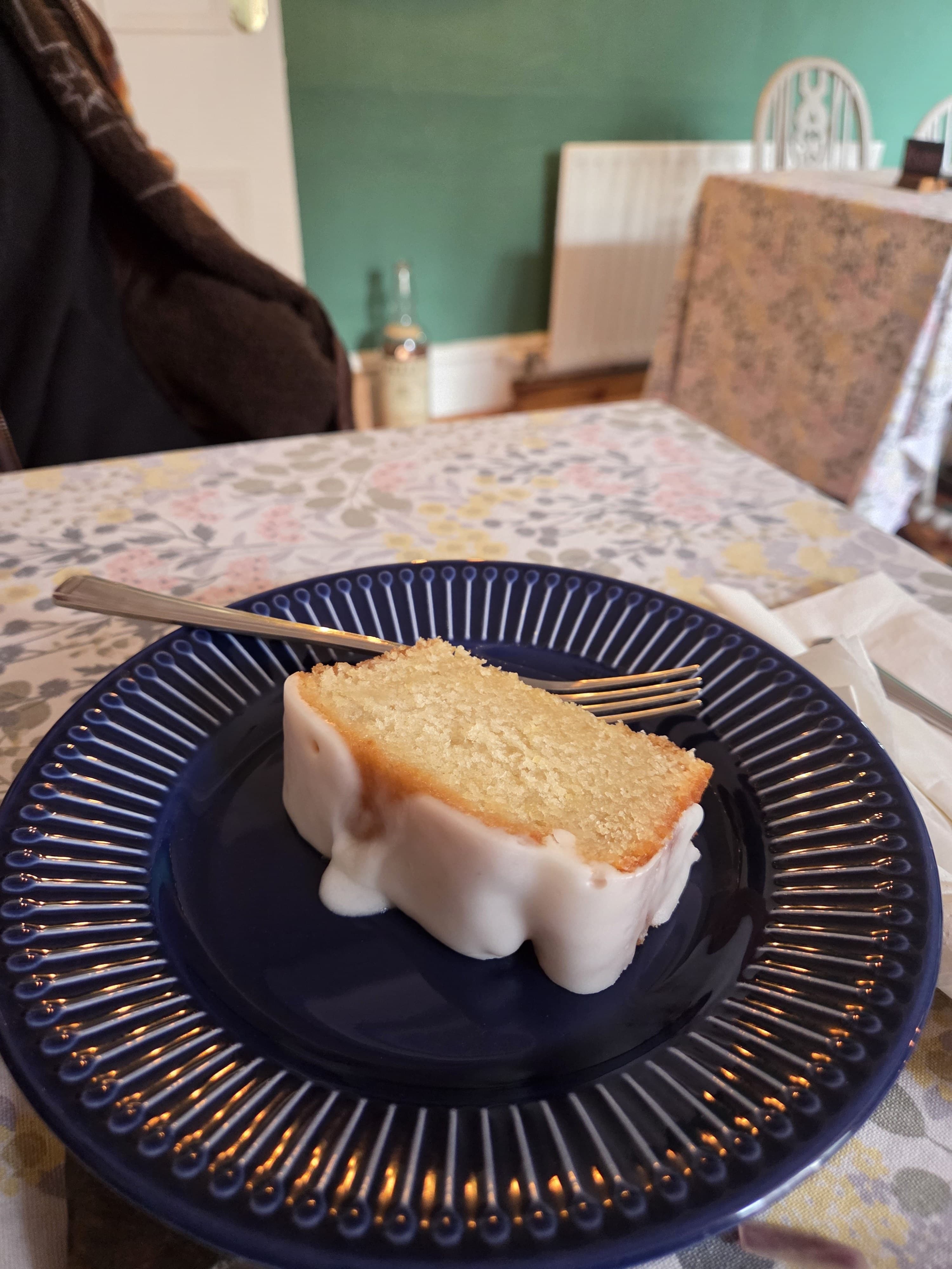 A generous slice of lemon drizzle cake on a deep blue plate