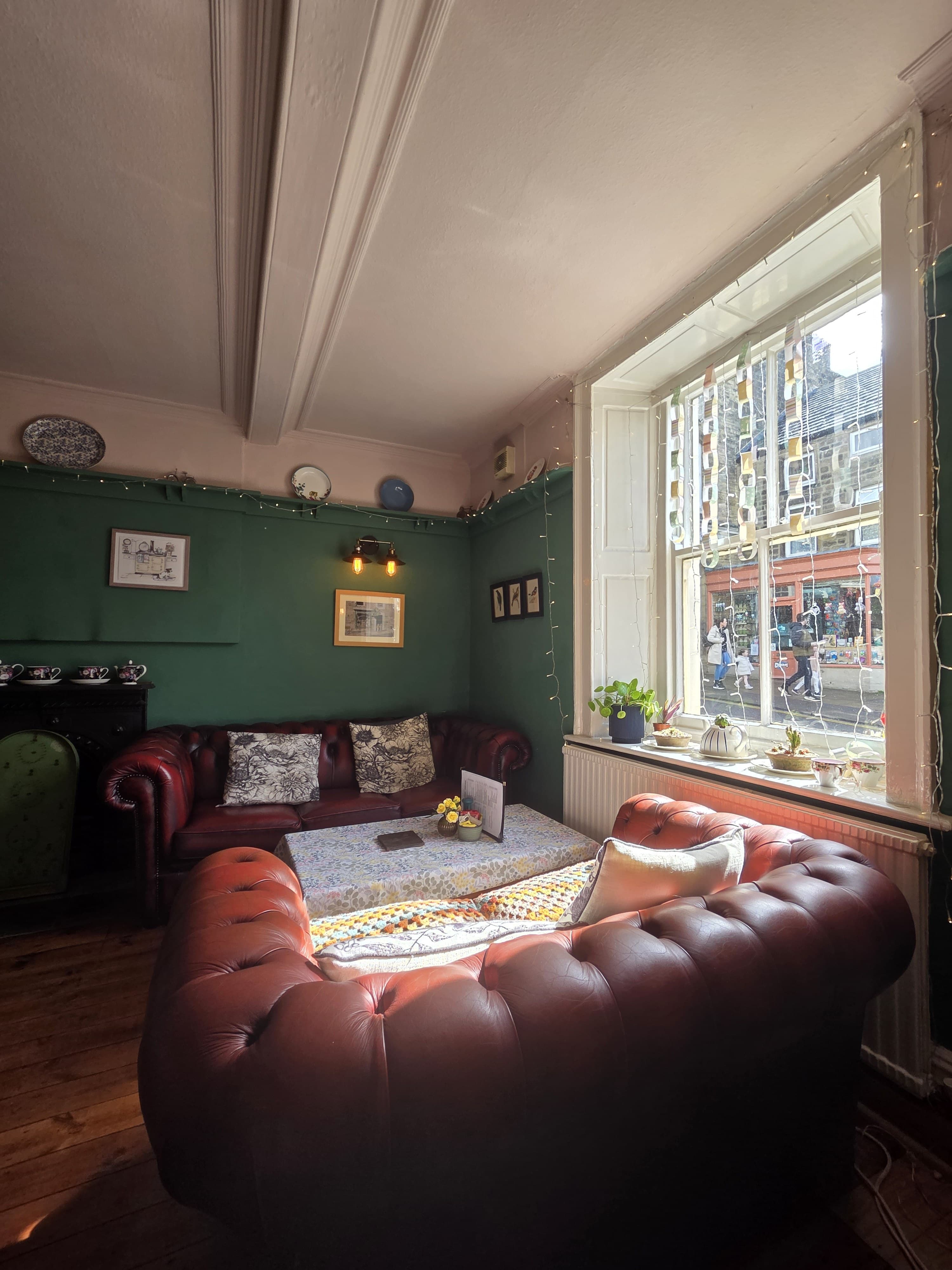 The cosy Chesterfield sofa room at Talbot House, with fairy lights, vintage prints and a window onto the High Street